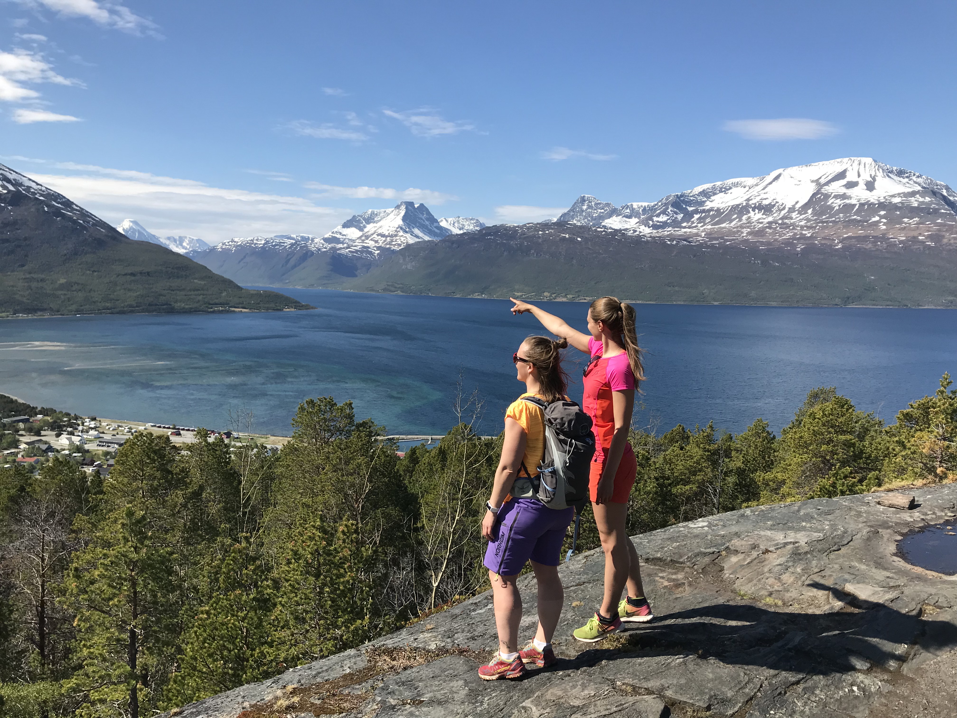 Two people on a walk to Svarteberget, with the fjord an lyngenalps in the background