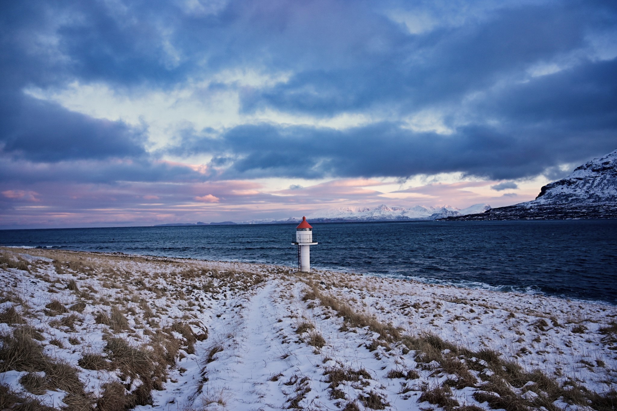 Small lighthouse by the sea and snow in the ground
