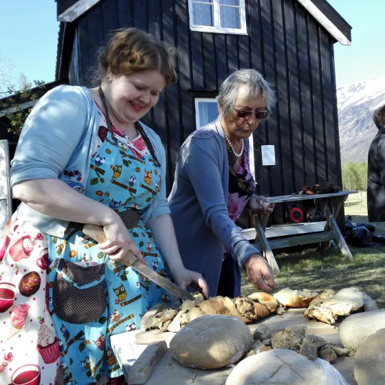 Two women baking bread outdoors