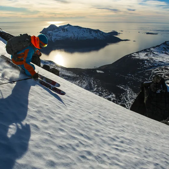 På ski nedover en fjellside i Lyngsalpene under midnattsolen