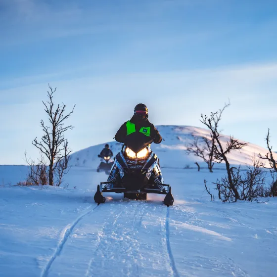 En person på snøskuter som kjører etter løype