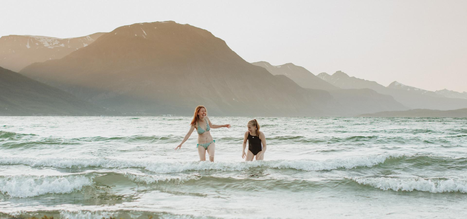 Two girls running and laughing in low water on a sea beach