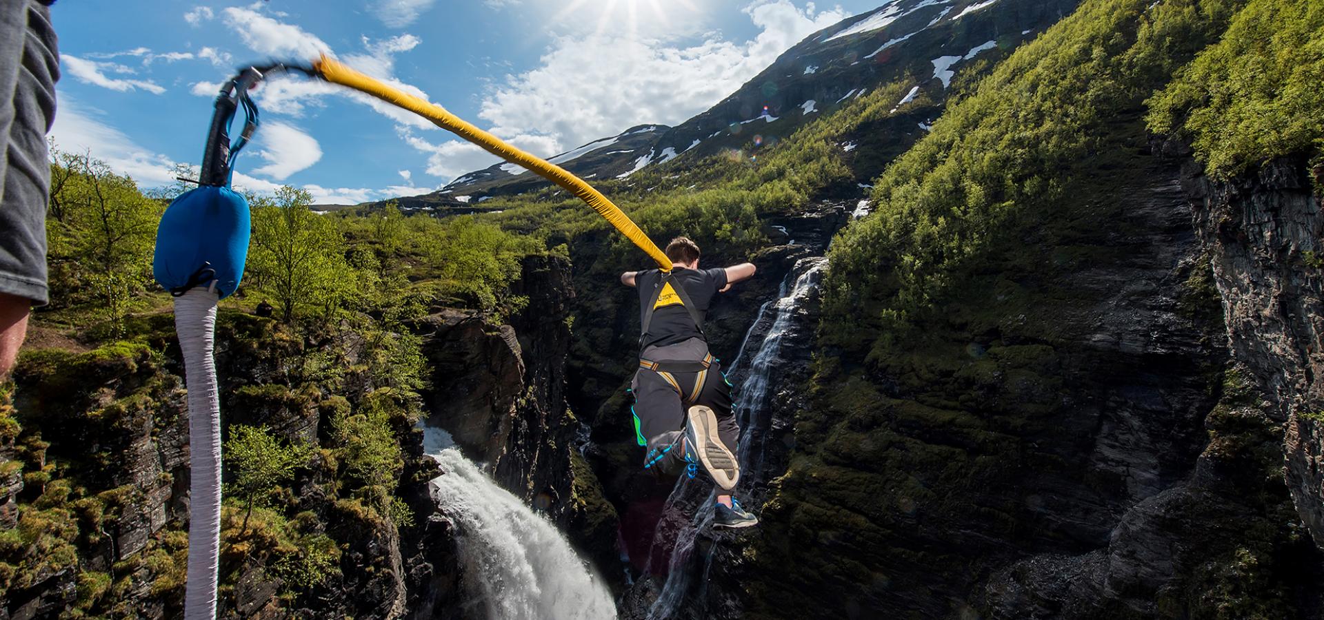 Person doing a bungee jump near a waterfall