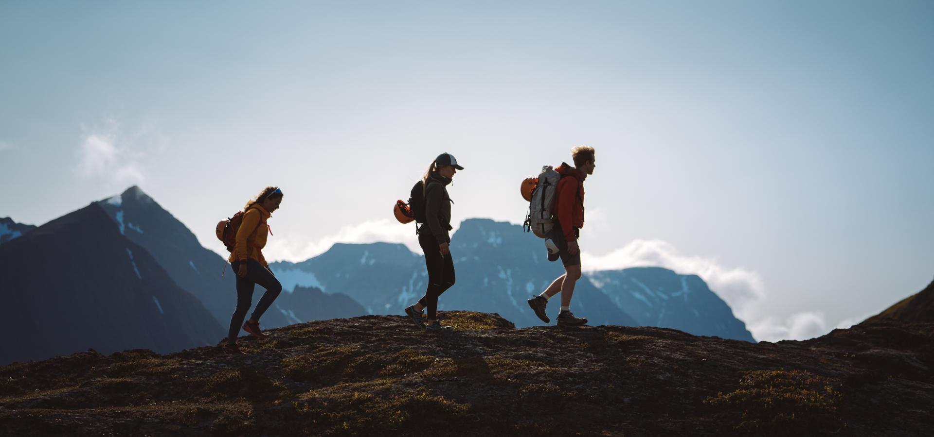 3 persons hiking in the Lyngen Alps, seen as siluettes