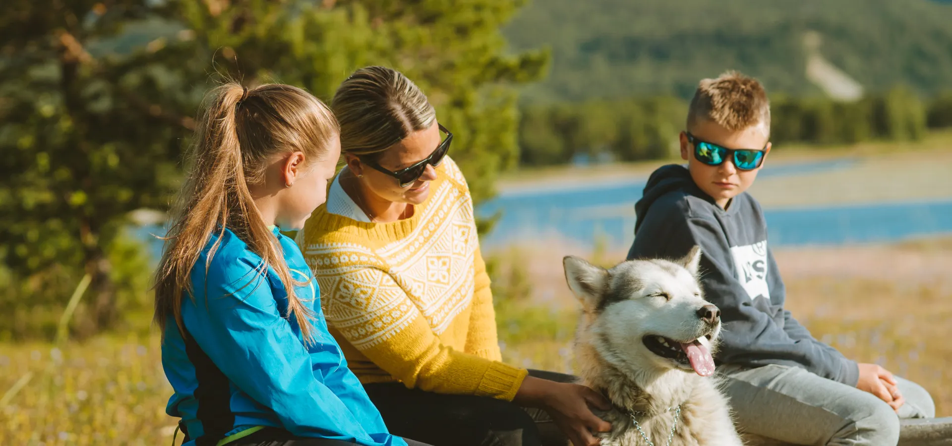 Familie med hund som sitter i fjæra