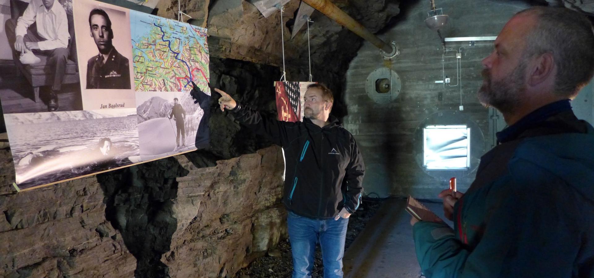 A guide showing the exhibition to a visitor, within a bunkers