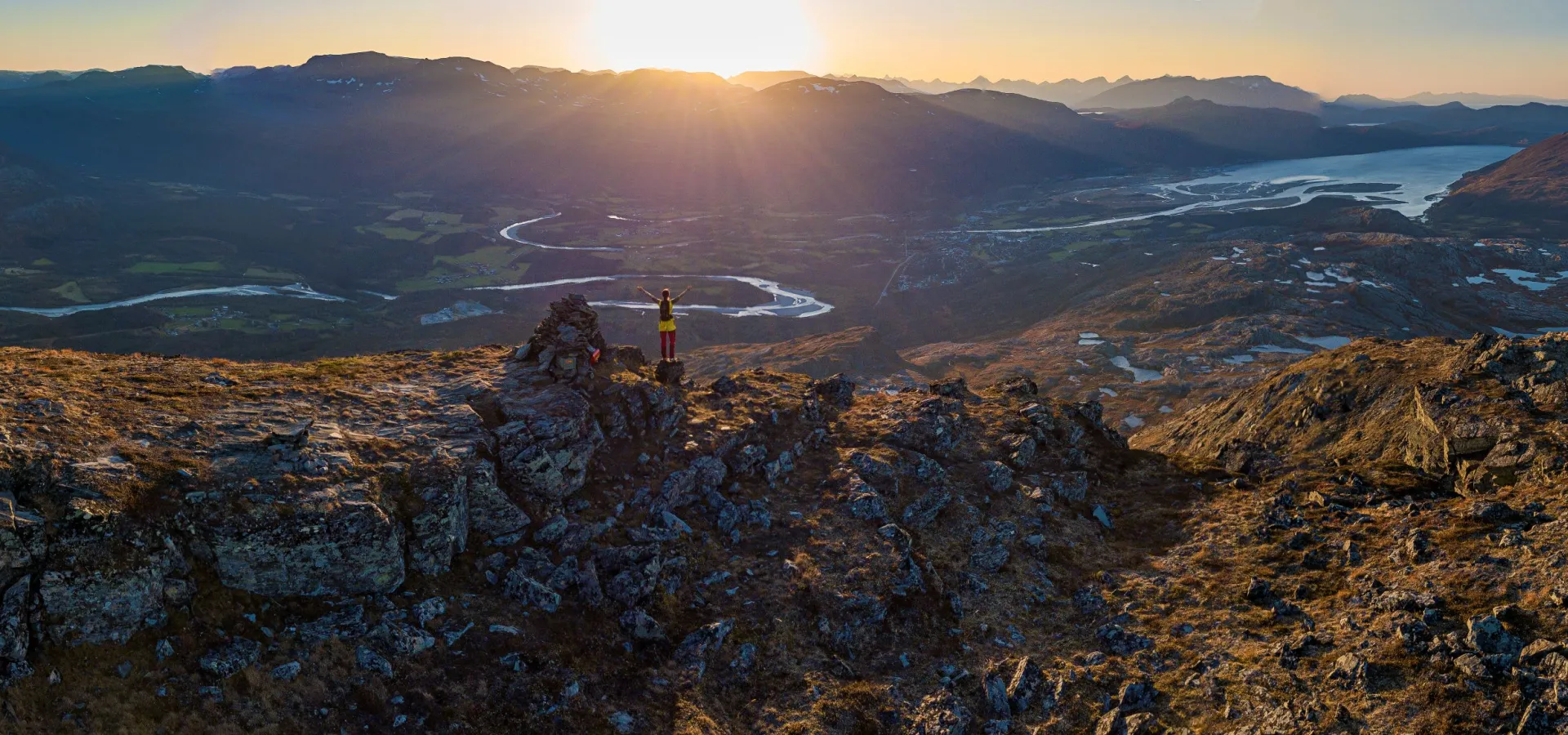 Person enjoying the view of Storslett from the peak Jyppyrä in the evening sun
