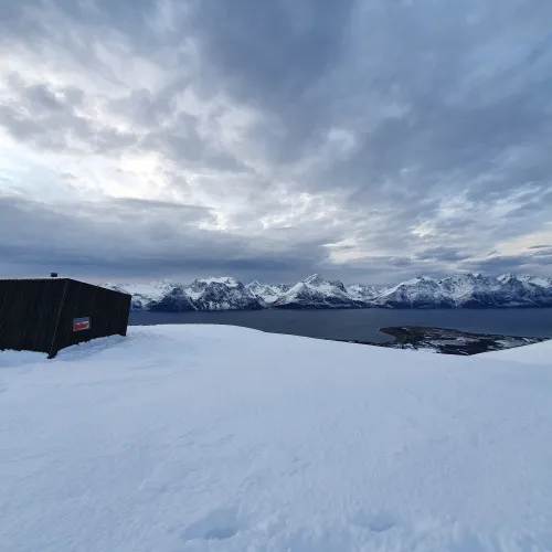 Dagsturhytta på Dalberget om vinteren med Lyngsalpene i bakgrunnen