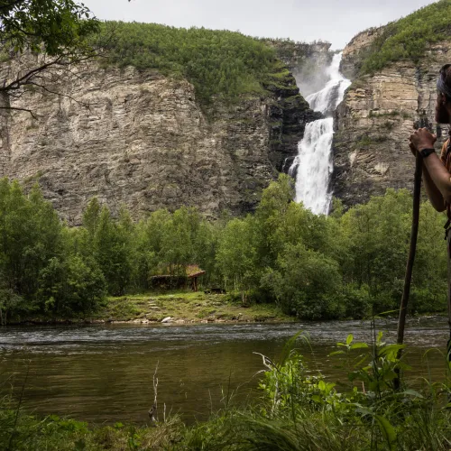 Hiker looking across the river towards a waterfall