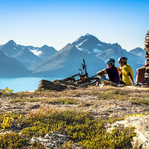 sitter ved en varde og ser over Lyngenfjorden til Lyngsalpene