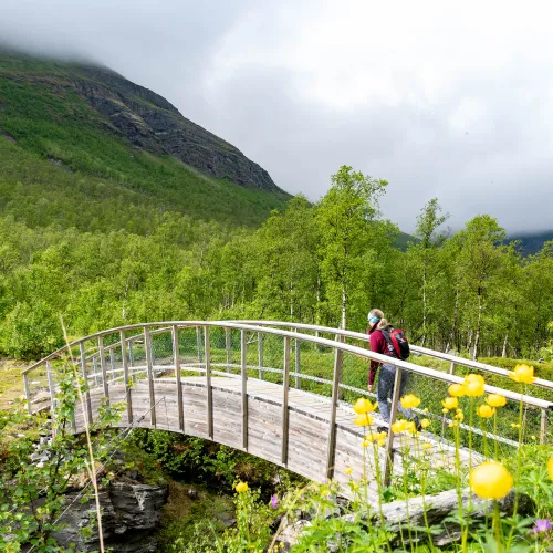 En dame går over en bru på vei til baalsruudhula i Manndalen