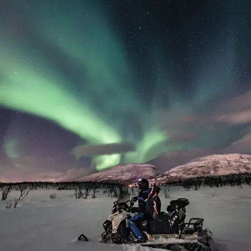 Snowmobiling under the northern lights in the Lyngen Alps, Northern Norway