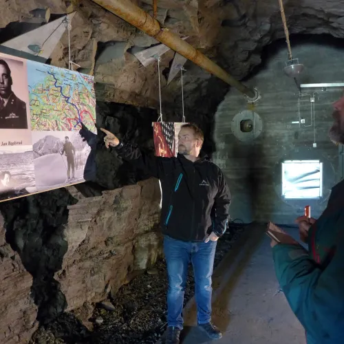 A guide showing the exhibition to a visitor, within a bunkers