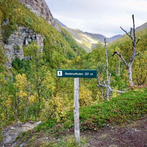 Signpost with "Baalsrudhula 50m" in a green valley