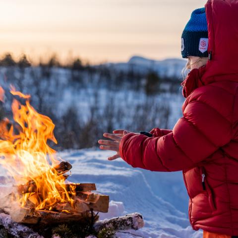 Barn som varmer seg ved bålet en vintersdag i Lyngen, Nord Norge