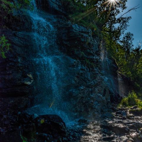 A small waterfall in the shadows and the sun shining