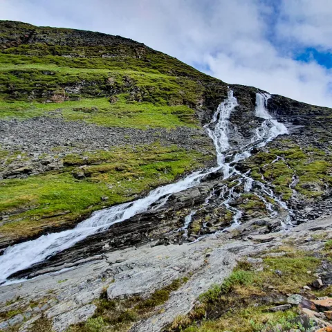 A waterfall flowing down a green lush mountain side