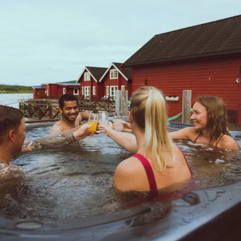 4 persons in a outdoor jacuzzi, red sea side cabins in the background