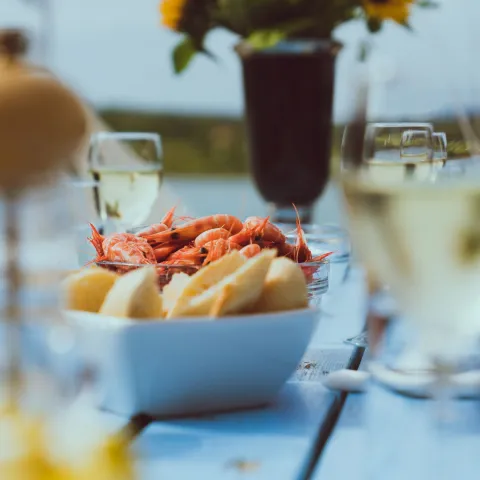 A summer table with glasses of wine, bowls with with bread and shrimps