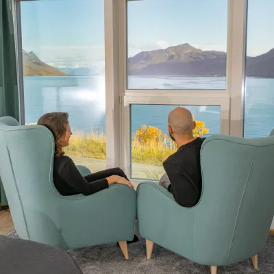To personer som ser utover fjorden fra en suite hos Arctic Panorama Lodge