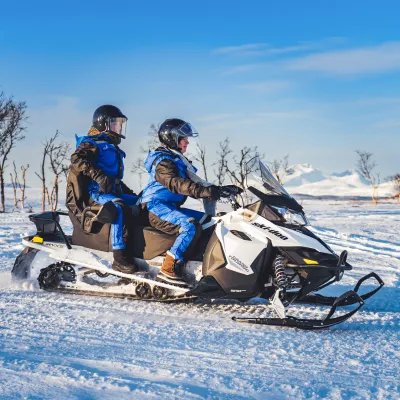 Two people riding a snowmobile.