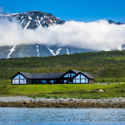 Lyngen Experience Lodge med Lyngsalpene i bakgrunn og Ullsfjorden foran