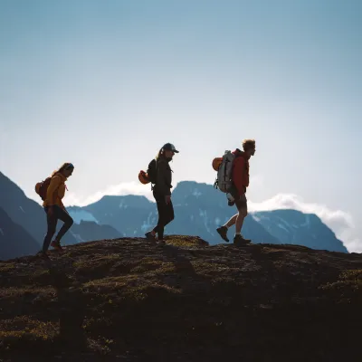 3 persons hiking in the Lyngen Alps, seen as siluettes
