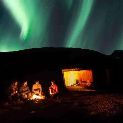 People enjoying the Northern Lights in a cabin by the Lyngenfjord
