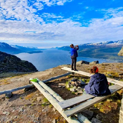 To personer nyter utsikten fra toppen av Bollmannsveien og ser fjorden og Lyngsalpene i det fjerne