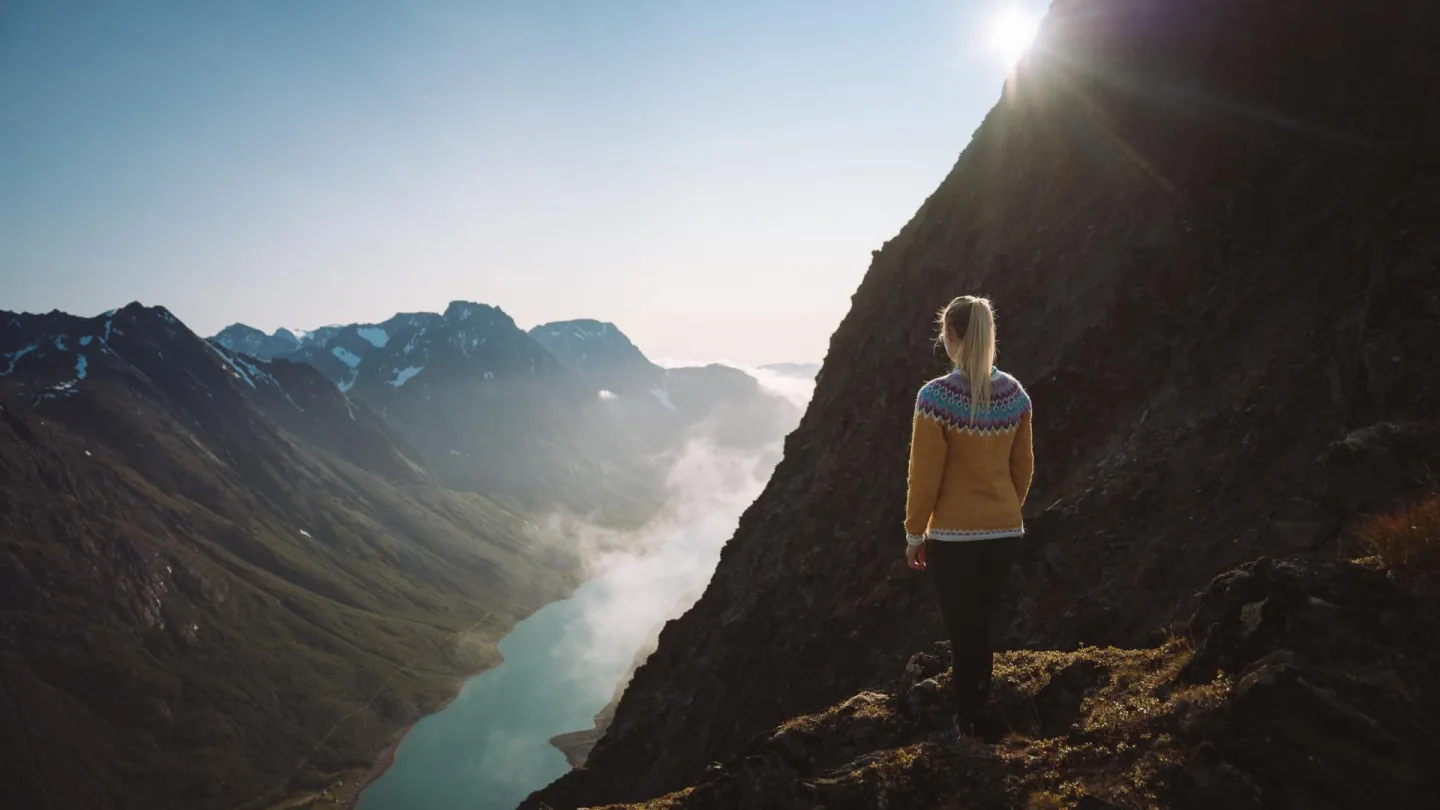 Dame på toppen av et fjell, ser ut over havet