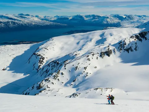 2 personer går på ski i fjellet