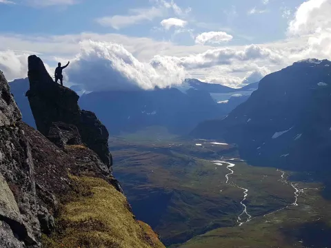 En person står høyt opp og ser utover dalen