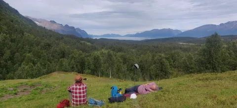 Tre mennesker slapper av på en grønn slette.