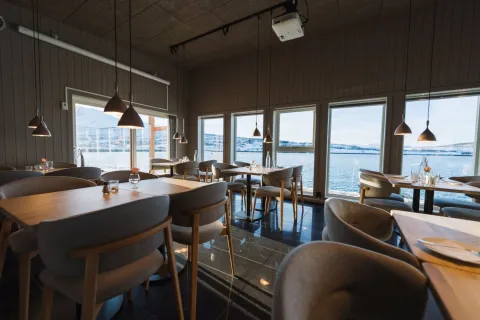 Restauranten Bøteriet med stoler og bord, panoramavinduer med utsikt til fjorden