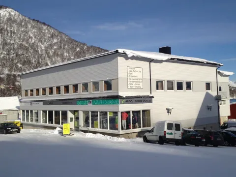 En hvit bygning med butikkvinduer i første etasjen. Tatt på en solrik vintersdag