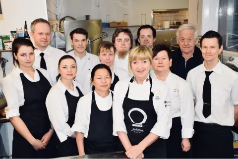 Bilde av personalet ved caféen, alle kledd i hvitt og med sorte forklær.