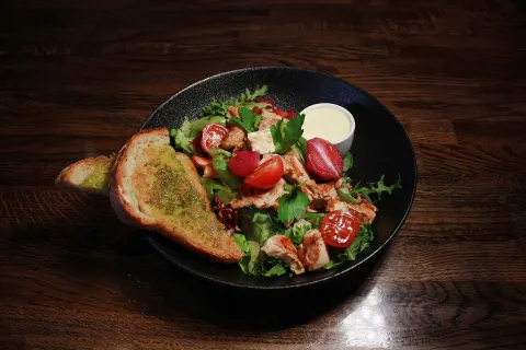 Fargerik salat i en sort skål med brød på siden