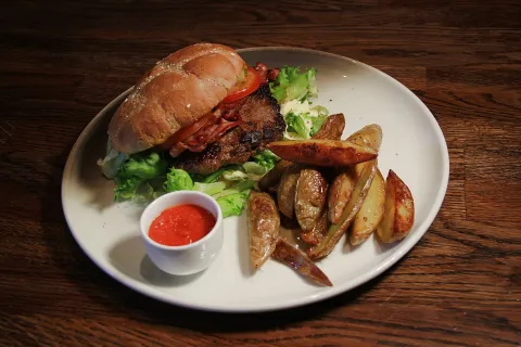 Burger med brød og stekte potetbåter på en hvit tallerken