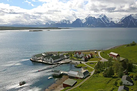 Dronebilde av fiskeværet Havnnes, med fjorden og Lyngsalpene i bakgrunnen