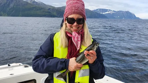 En kvinne holder opp fisken hun har fanget