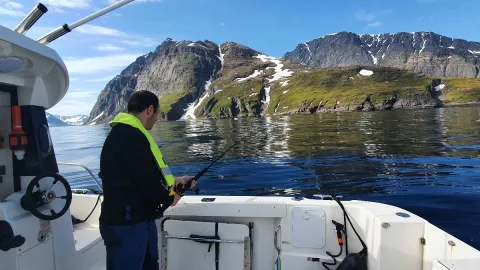 En mann ombord i en båt som står og fisker