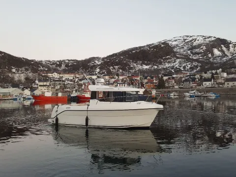 En hvit liten fritidsfiskebåt i havna på Skjervøy